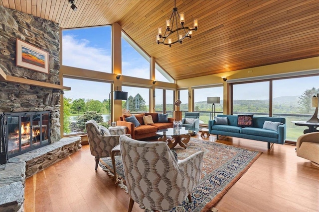 83 Dewey Farm Rd, Stowe, VT 05672 - living area featuring wood ceiling, high vaulted ceiling, a chandelier, a stone fireplace, and plenty of natural light
