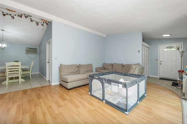4 Johns Dr Unit A, Hooksett, NH 03106 - living room with wood finished floors, an AC wall unit, a chandelier, baseboards, and a textured ceiling