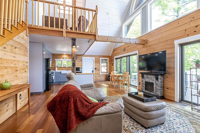 72 Auclair Rd, Middleton, NH 03887 - living room with wood walls, hardwood / wood-style floors, plenty of natural light, high vaulted ceiling, and stairway
