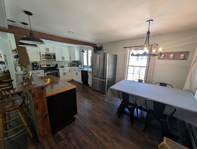 8 Main St, Bennington, NH 03442 - kitchen featuring stainless steel appliances, a peninsula, dark wood-style flooring, white cabinetry, and a breakfast bar