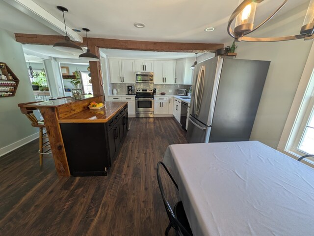 8 Main St, Bennington, NH 03442 - kitchen featuring appliances with stainless steel finishes, white cabinetry, dark wood-style flooring, hanging light fixtures, and a breakfast bar area