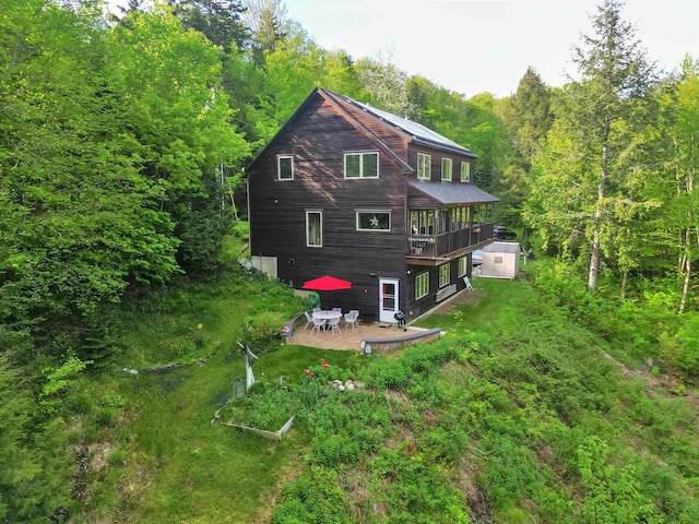 132 Lake Rd, Warren, VT 05674 - back of house featuring a patio, a view of trees, and a vegetable garden