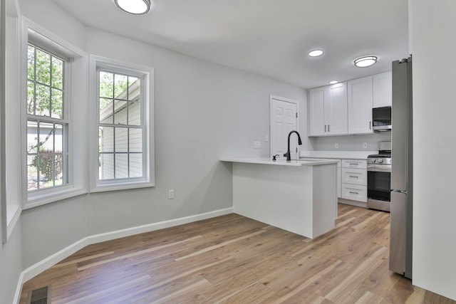 1465 Hooksett Rd Unit 403, Hooksett, NH 03106 - kitchen with stainless steel appliances, a peninsula, white cabinets, light wood-type flooring, and light countertops