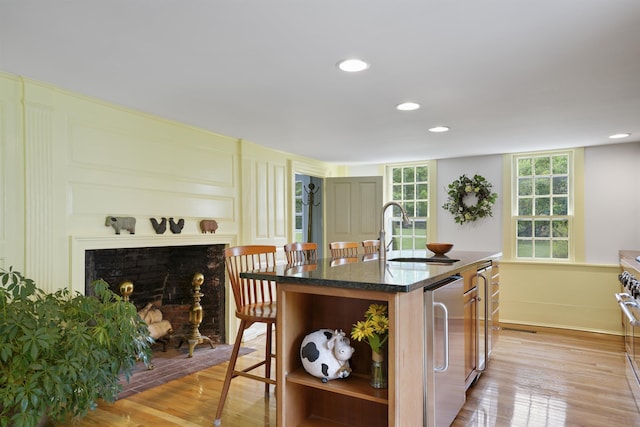 245-247 Danville Rd, Fremont, NH 03044 - kitchen featuring a sink, a breakfast bar area, a kitchen island with sink, light wood-style flooring, and dark stone countertops