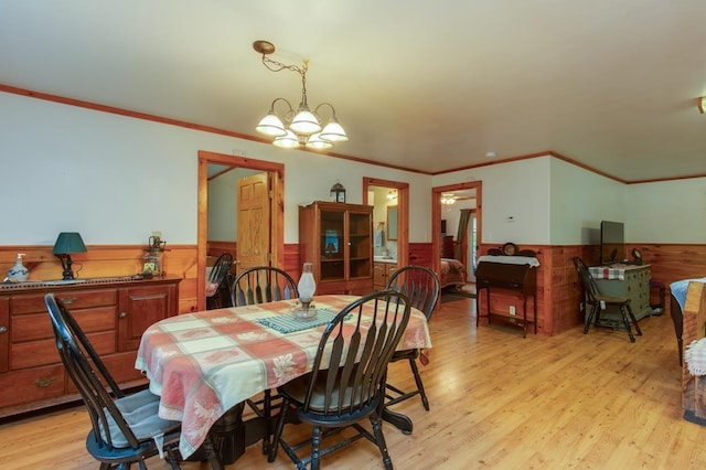 101 Mudgett Hill Rd, Loudon, NH 03307 - dining area featuring a wainscoted wall, crown molding, light wood-type flooring, a chandelier, and wooden walls