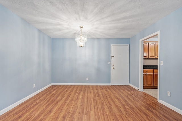 310 Brook Village Rd Unit 26, Nashua, NH 03062 - spare room featuring light wood-style flooring, a chandelier, baseboards, and a textured ceiling