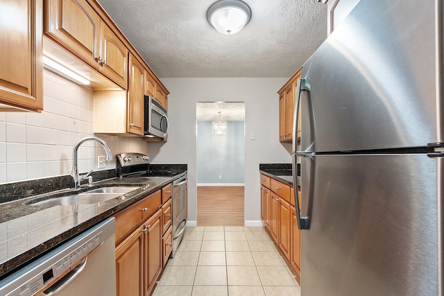 310 Brook Village Rd Unit 26, Nashua, NH 03062 - kitchen with appliances with stainless steel finishes, a sink, baseboards, brown cabinets, and a textured ceiling