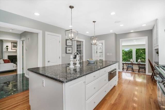 373 Whitford St, Manchester, NH 03104 - kitchen with a sink, a fireplace, white cabinets, a kitchen island with sink, and a chandelier