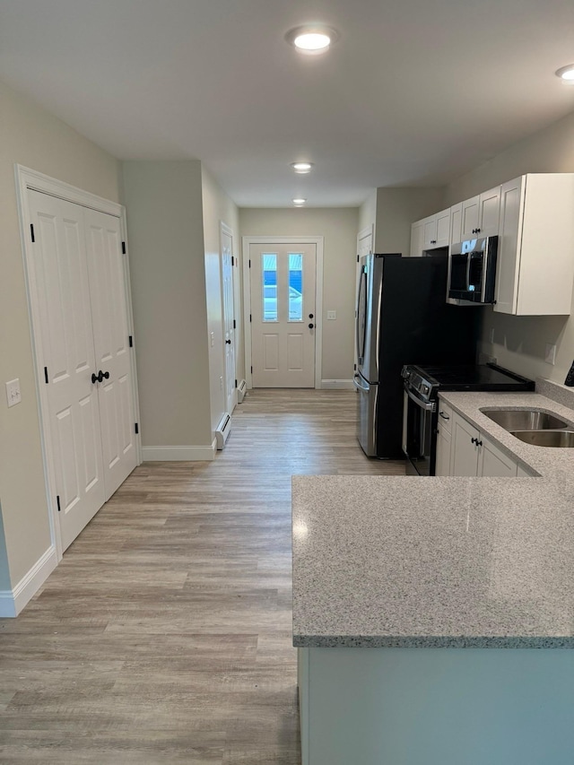 7 Willys Ln Unit 103, Milton, VT 05468 - kitchen featuring appliances with stainless steel finishes, baseboards, a sink, light wood finished floors, and light stone countertops