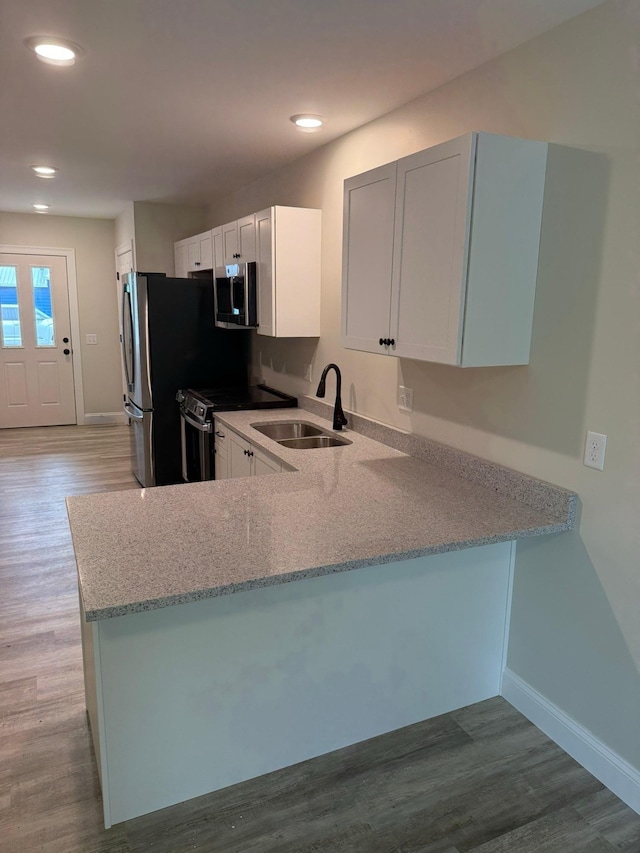 7 Willys Ln Unit 103, Milton, VT 05468 - kitchen with stainless steel appliances, a peninsula, light stone counters, baseboards, and recessed lighting