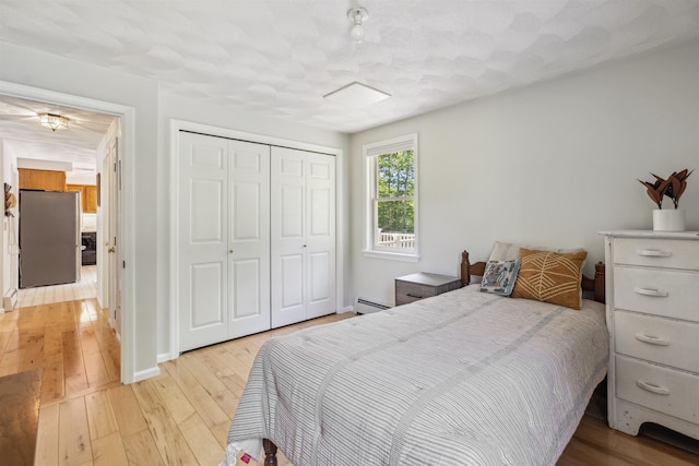 24 Theresa Ave, Salem, NH 03079 - bedroom with freestanding refrigerator, a baseboard heating unit, light wood-style floors, and a closet