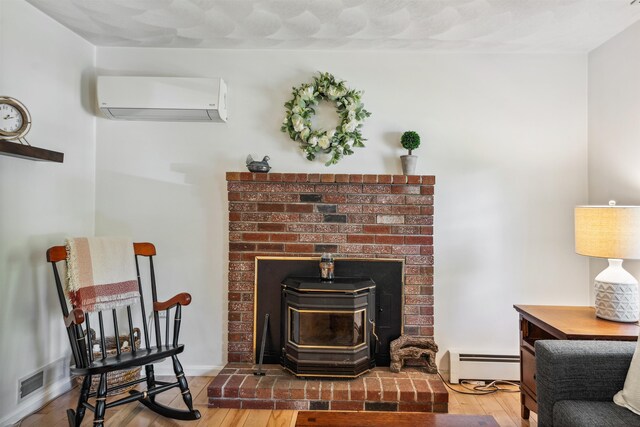 24 Theresa Ave, Salem, NH 03079 - detailed view of an AC wall unit, baseboard heating, a wood stove, and wood finished floors