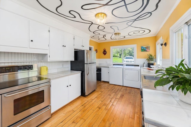 236 Main St, Jaffrey, NH 03452 - kitchen featuring stainless steel appliances, ornamental molding, white cabinetry, a wainscoted wall, and washer and dryer