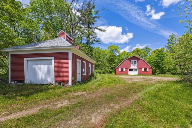 236 Main St, Jaffrey, NH 03452 - view of side of property featuring a garage, an outbuilding, a chimney, and a shingled roof