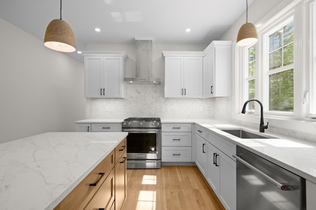 93 Stage Rd, Hampstead, NH 03841 - kitchen with appliances with stainless steel finishes, wall chimney range hood, a sink, light wood-type flooring, and decorative backsplash