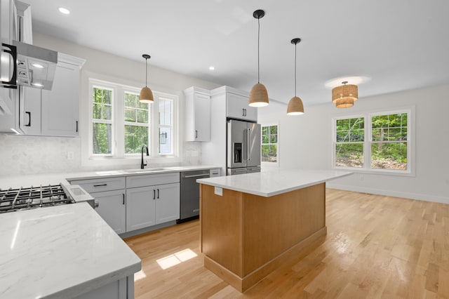 93 Stage Rd, Hampstead, NH 03841 - kitchen featuring stainless steel appliances, a sink, light wood-style floors, backsplash, and a kitchen island