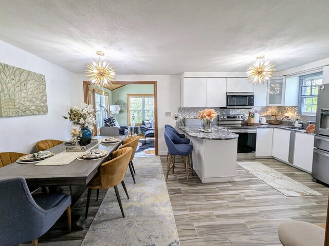 19 Bradford Dr, Salem, NH 03079 - kitchen with stainless steel appliances, a peninsula, white cabinetry, and a chandelier