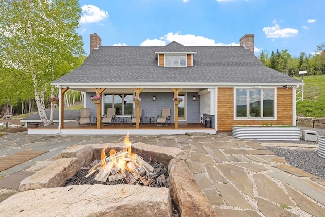 126 Stoddard Rd, Columbia, NH 03576 - back of house featuring a chimney, a fire pit, a shingled roof, and covered porch