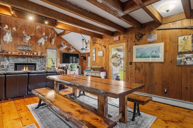 126 Stoddard Rd, Columbia, NH 03576 - dining space with wood walls, beamed ceiling, light wood finished floors, rail lighting, and a fireplace
