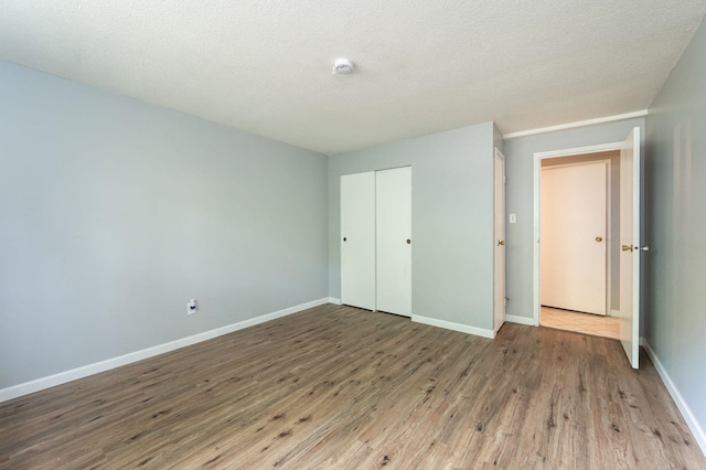 17 Silvestri Cir Unit 4, Derry, NH 03038 - unfurnished bedroom with wood finished floors, a closet, baseboards, and a textured ceiling