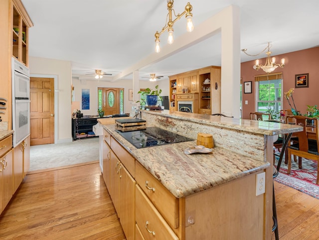 1851 York Street Ext, Poultney, VT 05764 - kitchen featuring black electric stovetop, open floor plan, a fireplace, a ceiling fan, and a kitchen bar