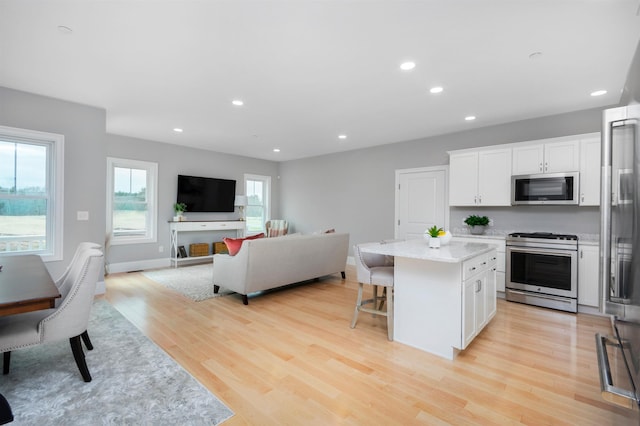 148 County Rd, Amherst, NH 03055 - kitchen featuring stainless steel appliances, a center island, white cabinets, light wood-style floors, and a breakfast bar area