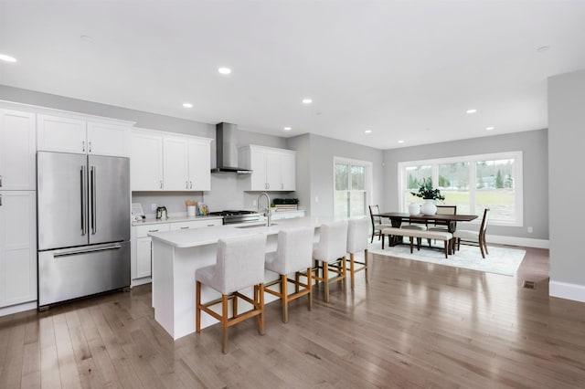 148 County Rd, Amherst, NH 03055 - kitchen with stainless steel appliances, wall chimney exhaust hood, a center island with sink, white cabinetry, and light countertops