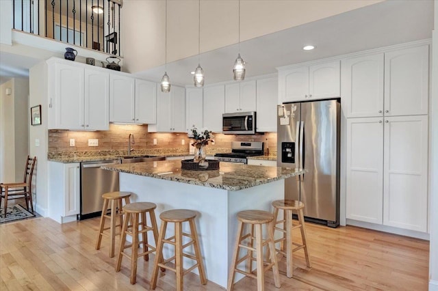 28A Black Walnut Ln Unit A, Jericho, VT 05465 - kitchen featuring stainless steel appliances, light wood-style flooring, a kitchen bar, recessed lighting, and a towering ceiling