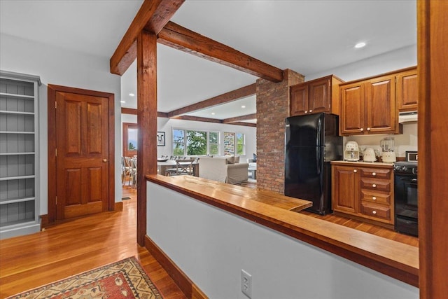 1444 Upper Hollow Rd, Stowe, VT 05672 - kitchen featuring black appliances, under cabinet range hood, light wood-type flooring, beamed ceiling, and brown cabinets