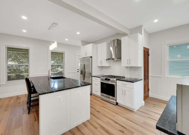 162 Sagamore St, Manchester, NH 03104 - kitchen with appliances with stainless steel finishes, wall chimney range hood, a sink, light wood finished floors, and white cabinetry