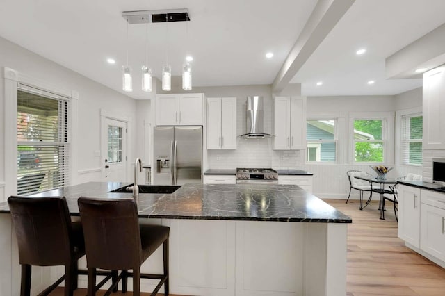 162 Sagamore St, Manchester, NH 03104 - kitchen featuring appliances with stainless steel finishes, a sink, wall chimney range hood, light wood-type flooring, and white cabinets