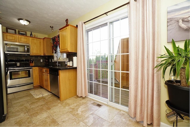 602 Silver St Unit 5, Manchester, NH 03103 - kitchen with appliances with stainless steel finishes, a sink, backsplash, dark countertops, and light stone finish floors