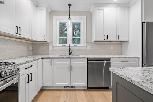 214 Pembroke St Unit A, Pembroke, NH 03275 - kitchen featuring a sink, appliances with stainless steel finishes, white cabinets, hanging light fixtures, and decorative backsplash