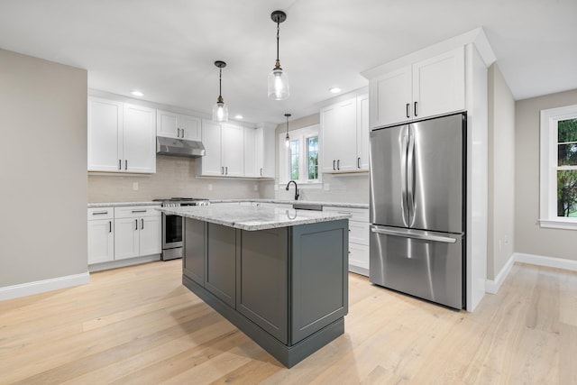 214 Pembroke St Unit A, Pembroke, NH 03275 - kitchen featuring stainless steel appliances, under cabinet range hood, white cabinets, baseboards, and decorative backsplash