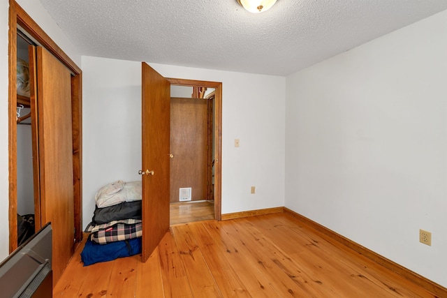 72 Mather Rd, Tamworth, NH 03886 - unfurnished bedroom with light wood finished floors, baseboards, a closet, and a textured ceiling