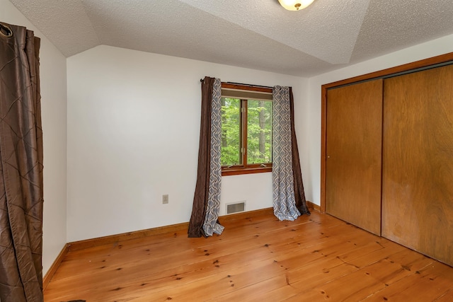 72 Mather Rd, Tamworth, NH 03886 - unfurnished bedroom with wood-type flooring, a textured ceiling, a closet, lofted ceiling, and baseboards