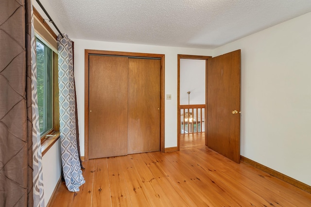 72 Mather Rd, Tamworth, NH 03886 - unfurnished bedroom featuring light wood-type flooring, a textured ceiling, baseboards, and a closet