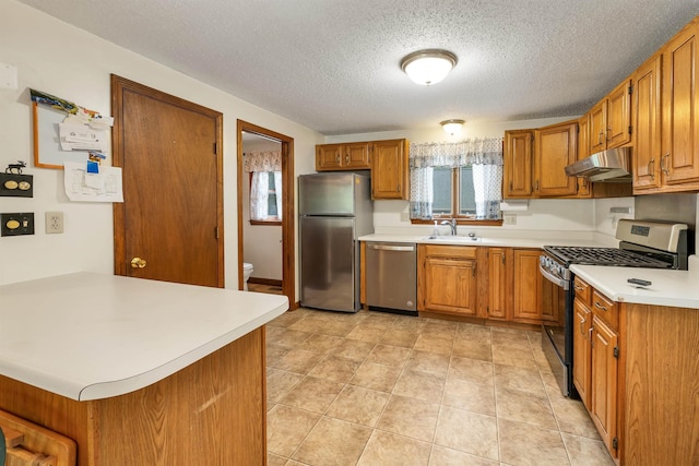 72 Mather Rd, Tamworth, NH 03886 - kitchen featuring stainless steel appliances, under cabinet range hood, a sink, brown cabinetry, and light countertops