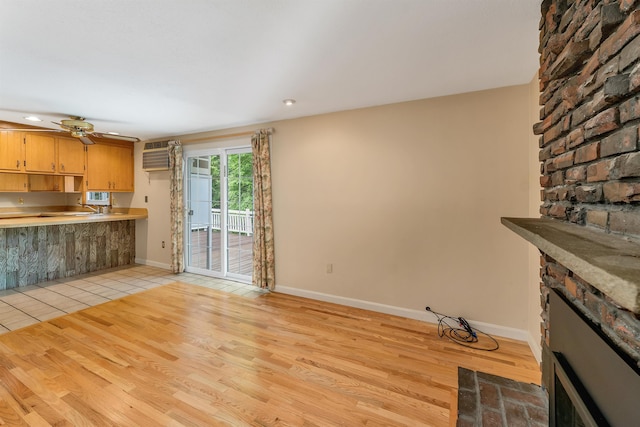 1 Pepperell Cir, Nashua, NH 03062 - unfurnished living room with a fireplace, ceiling fan, light wood finished floors, a wall mounted AC, and baseboards