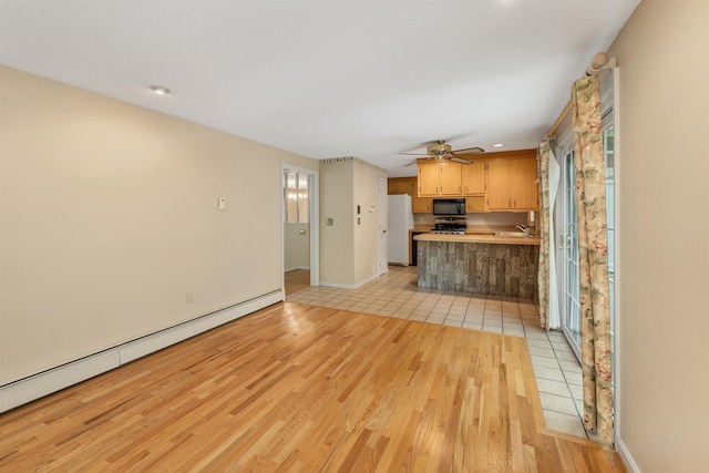 1 Pepperell Cir, Nashua, NH 03062 - kitchen with freestanding refrigerator, baseboard heating, black microwave, a sink, and light wood-style floors