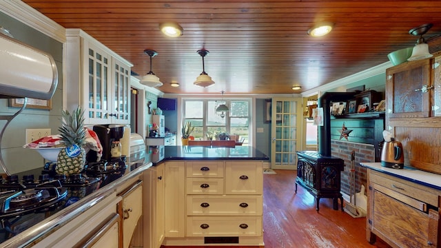 358 S Main St, Whiting, VT 05778 - kitchen with a peninsula, black stovetop, a wood stove, wood finished floors, and glass insert cabinets
