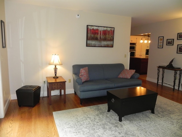1782 Old Creamery Rd, Williston, VT 05495 - living room featuring wood finished floors, a chandelier, and baseboards