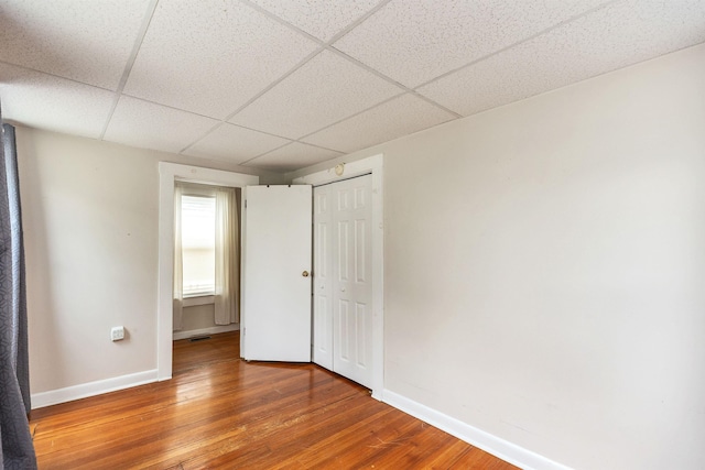 247 Prospect St, Manchester, NH 03104 - unfurnished bedroom featuring wood finished floors, baseboards, a paneled ceiling, and a closet