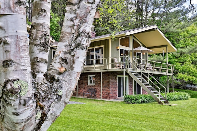 775 E Lake Rd, Ludlow, VT 05149 - back of property with board and batten siding, brick siding, a yard, stairs, and a wooden deck
