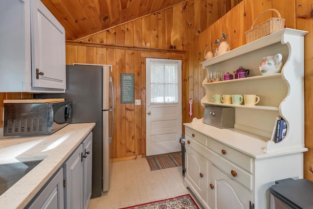 22 Shore Dr, Middleton, NH 03887 - kitchen with black microwave, vaulted ceiling, wooden ceiling, wood walls, and light wood-type flooring