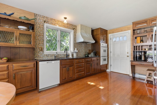 79 Silver St, Dover, NH 03820 - kitchen featuring white appliances, premium range hood, a sink, light wood-type flooring, and brown cabinetry