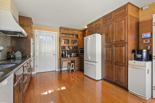 79 Silver St, Dover, NH 03820 - kitchen featuring white appliances, custom range hood, tasteful backsplash, light wood finished floors, and dark stone countertops