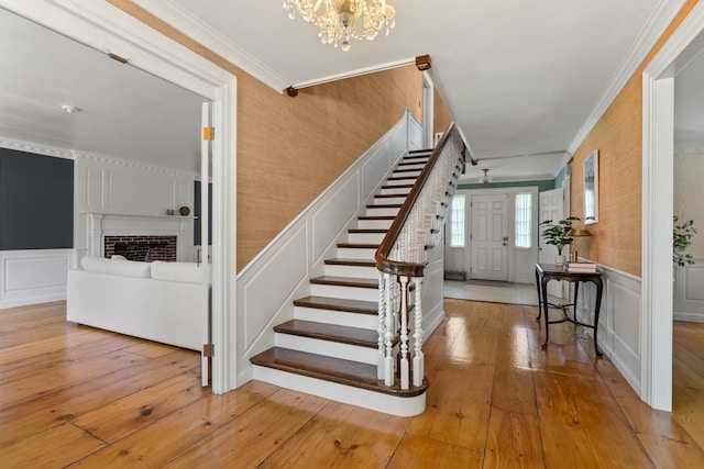 79 Silver St, Dover, NH 03820 - stairs featuring a decorative wall, crown molding, a chandelier, hardwood / wood-style floors, and a wainscoted wall