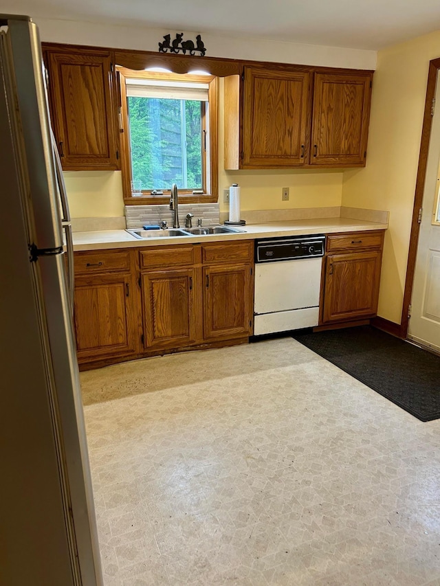 348 Ridge Rd, Northwood, NH 03261 - kitchen with dishwasher, a sink, freestanding refrigerator, brown cabinetry, and light countertops