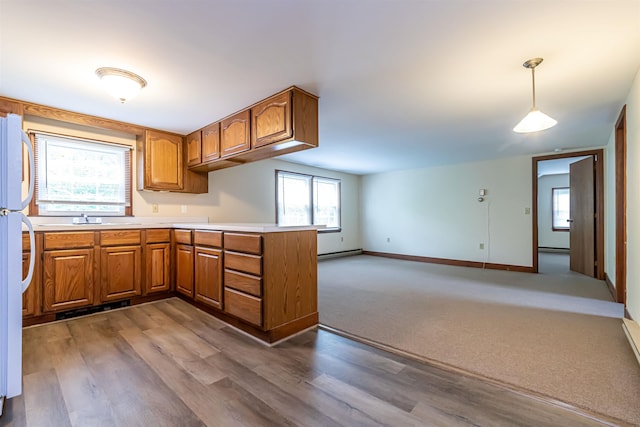 212 W Main St, Hillsborough, NH 03244 - kitchen with brown cabinetry, a baseboard radiator, a peninsula, open floor plan, and baseboards